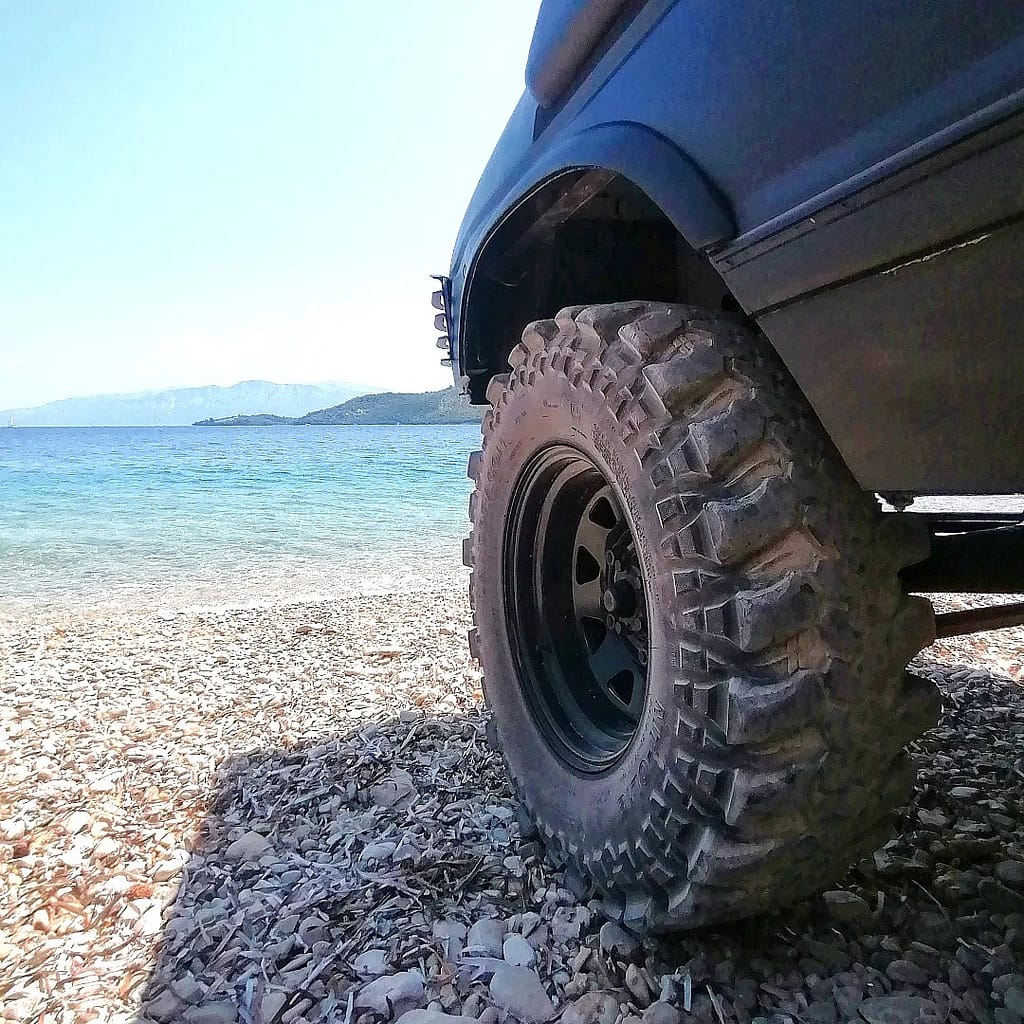 La robustezza della Land Rover, pronta per affrontare terreni impervi, simbolo di avventura nel tour 4x4 a Lefkada, con la splendida spiaggia di Fteri e il mare che fanno da sfondo a questa esperienza unica.