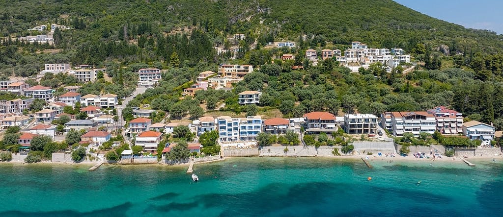 Vista della costa di Perigiali dal mare con il Greek Beach House al centro, immerso tra acque dai colori smeraldini e sfumature turchesi.