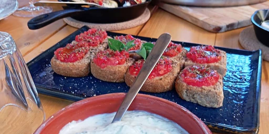 Un assaggio di Dakos, la versione greca della bruschetta italiana, serviti durante una cena privata dal campo alla tavola, offrendo un'esperienza unica e indimenticabile, diversa dalla solita cena al ristorante.