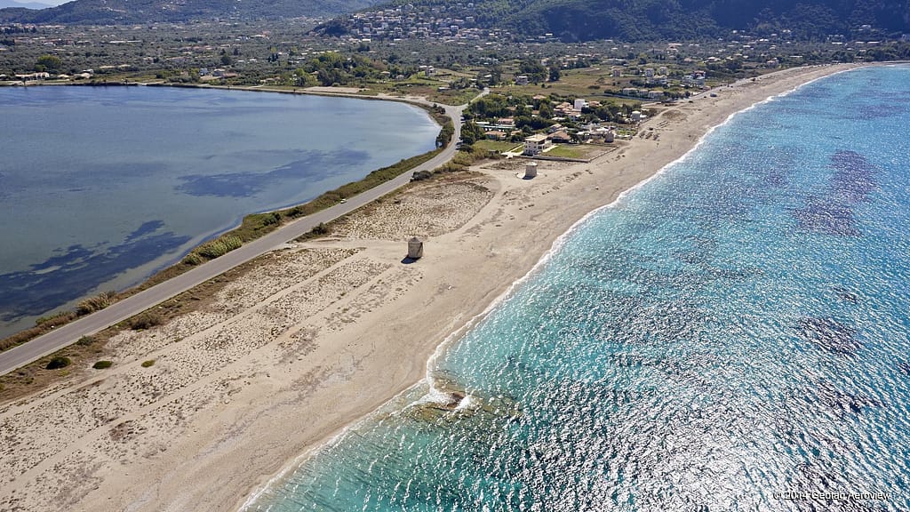 Spiaggia di Agios Iannis a Lefkada con il mare cristallino da un lato e la laguna tranquilla dall'altro, immersa in un paesaggio onirico..