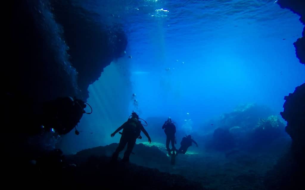 Subacquei esplorano le acque cristalline di Meganissi, entrando nella storica Grotta Papanikolis, un rifugio sottomarino usato durante la Grande Guerra.