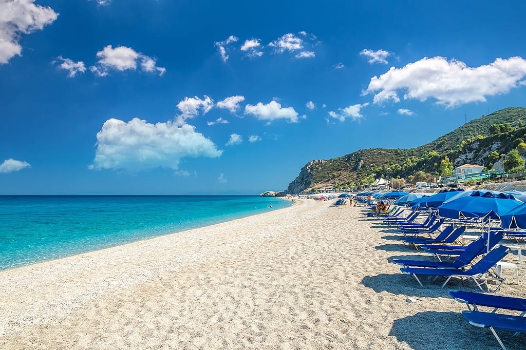 Un'incantevole vista di Kathisma Beach dalla prospettiva opposta, dove il mare turchese si fonde con il cielo azzurro, creando uno scenario da sogno. L’orizzonte si perde nell'infinito, regalando una sensazione di pace e serenità.