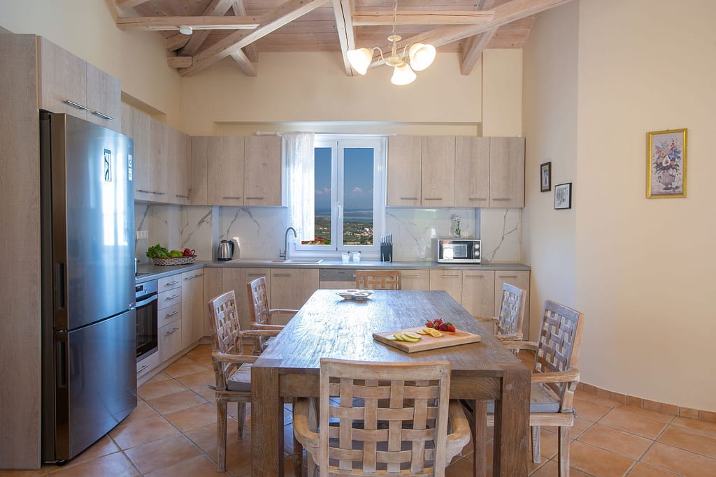 Angolo cucina di Villa Petra, completamente attrezzata, con una finestra che offre una splendida vista mare mentre si lavano i piatti nella lavastoviglie.