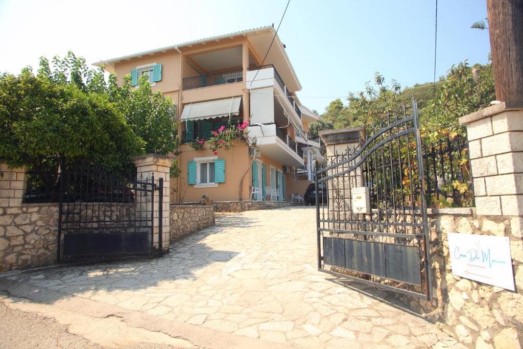 Casa Maria ad Agios Ioannis, Lefkada: facciata della struttura con balconi, persiane azzurre e giardino esterno