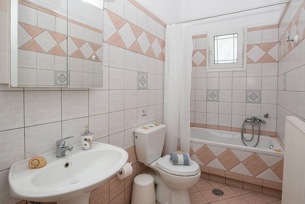 Bagno dell'appartamento con una camera da letto di Niki Apts, completo di vasca e doccia, situato ad Agios Ioannis.