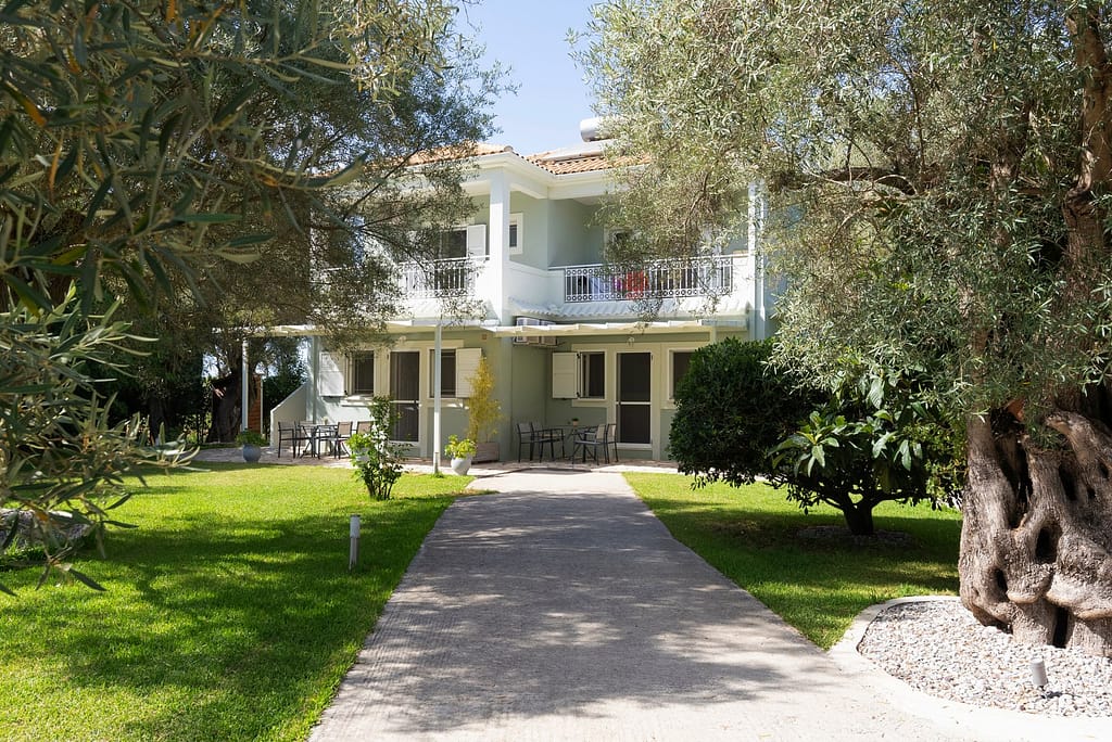 Vista esterna dell'appartamento al primo piano di Niki Apts, con due balconi che offrono una vista sul giardino e sulle colline circostanti.