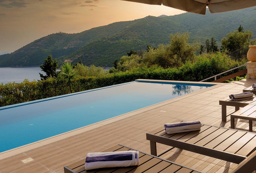 Piscina e area relax di una delle Ionian Diamond Villas con uno scorcio della baia di Rouda al tramonto.