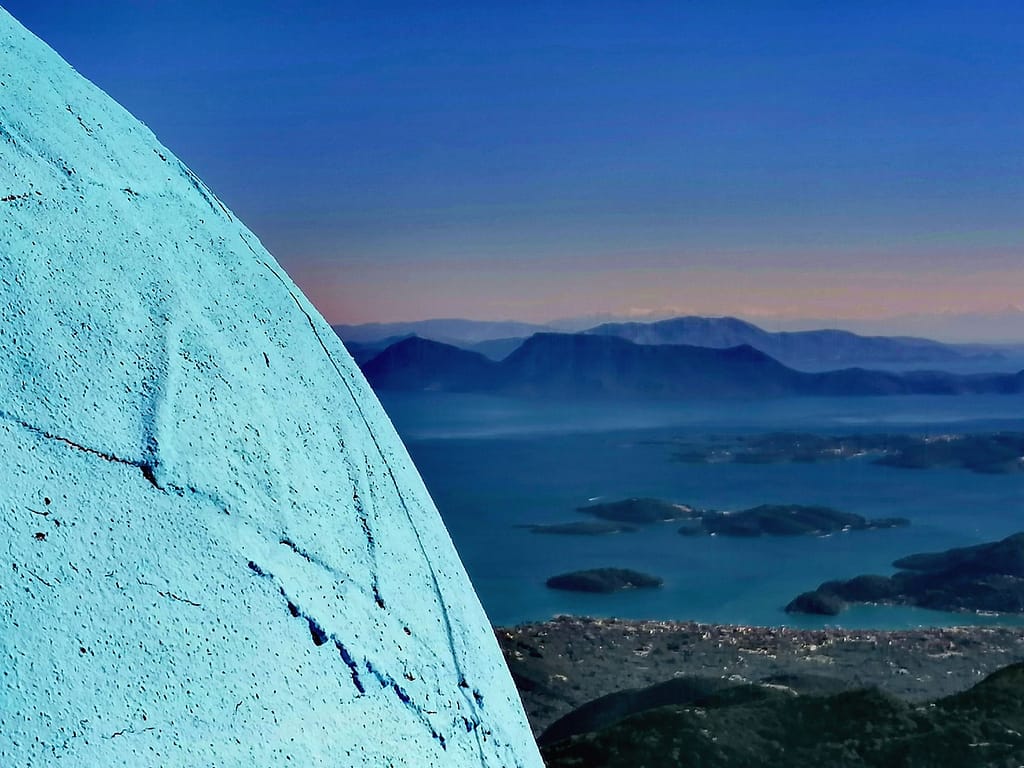 Grande roccia tondeggiante di Lefkada in primo piano, che simboleggia l’isola, con il magnifico panorama dell’arcipelago delle Isole del Principe sullo sfondo.