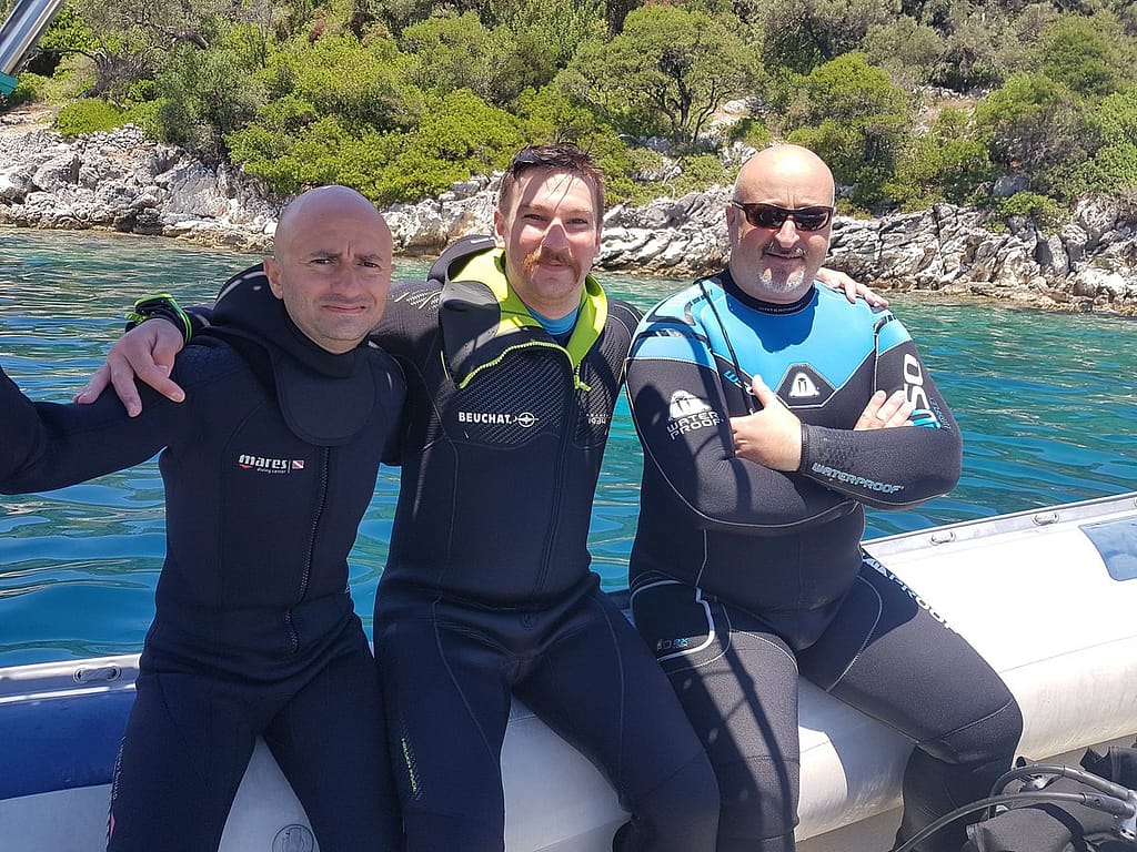 Gruppo di amici a bordo del gommone del Lefkas Diving Center, pronti per l'immersione nella famosa Grotta Papanicolis a Lefkada, uno dei siti più affascinanti per le immersioni subacquee.