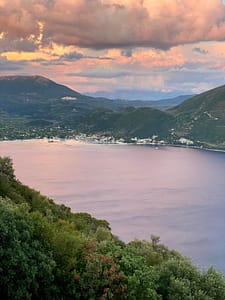 Riflessi rosati al tramonto nella baia di Vassiliki Alt Text: Il cielo si tinge di rosa al tramonto, riflettendosi sulle acque calme della baia di Vassiliki a Lefkada.