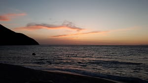 — “Tramonto su Agios Ioannis, con cielo dai toni caldi e mare calmo.