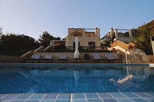 Dettaglio della piscina delle Ionian Diamond Villas con rivestimento in micro tessere, incorniciata da un cielo azzurro limpido e le ville sullo sfondo.