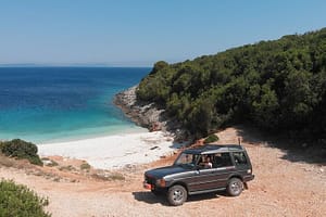 Giannis in riva al mare alla guida della sua jeep durante un tour emozionante lungo le vie sterrate di Lefkada, circondato da paesaggi spettacolari.