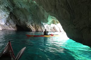 e equipaggi di kayak entrano in una suggestiva grotta a Meganissi, esplorando le meraviglie naturali della costa ionica durante il tour in kayak.