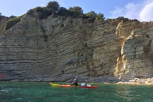 Un kayak esplora le acque cristalline sotto la costa di Kastos, navigando tra le meravigliose scogliere e godendo della pace e della serenità del paesaggio marino incontaminato.