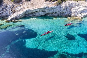 Kayak che galleggiano sopra un fondo marino trasparente, con riflessi acqua marina che creano un'atmosfera sospesa e suggestiva.