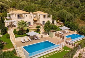 Vista degli esterni delle Ionian Diamond Villas, con terrazze panoramiche, due piscine private, giardini curati e aree relax attrezzate con lettini e docce esterne.