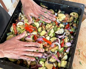 Immagine di una teglia piena di verdure tagliate alla micro farm, pronte per essere cotte nel forno a legna durante un corso di cucina.