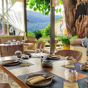 Tavolo apparecchiato al Ristorante Mastelo a Katouna, con piatti tradizionali e posate, pronto per accogliere gli ospiti in un'atmosfera accogliente e rustica.
