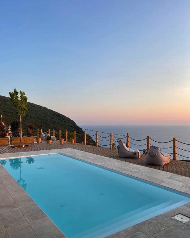 La piscina della Eunoia Suite al tramonto, con la costa occidentale verde e rigogliosa che si affaccia sul mare cristallino.