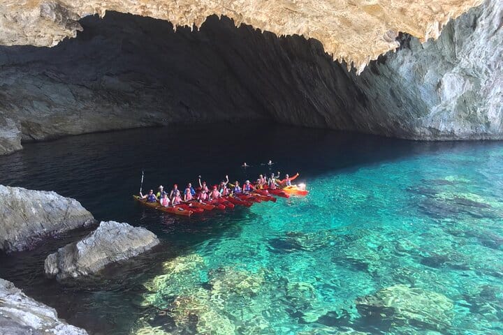 Un gruppo di partecipanti al tour in kayak, ripreso da un drone all'interno della Grotta di Papanikolis, con il contrasto tra il fondo marino e le rocce circostanti.