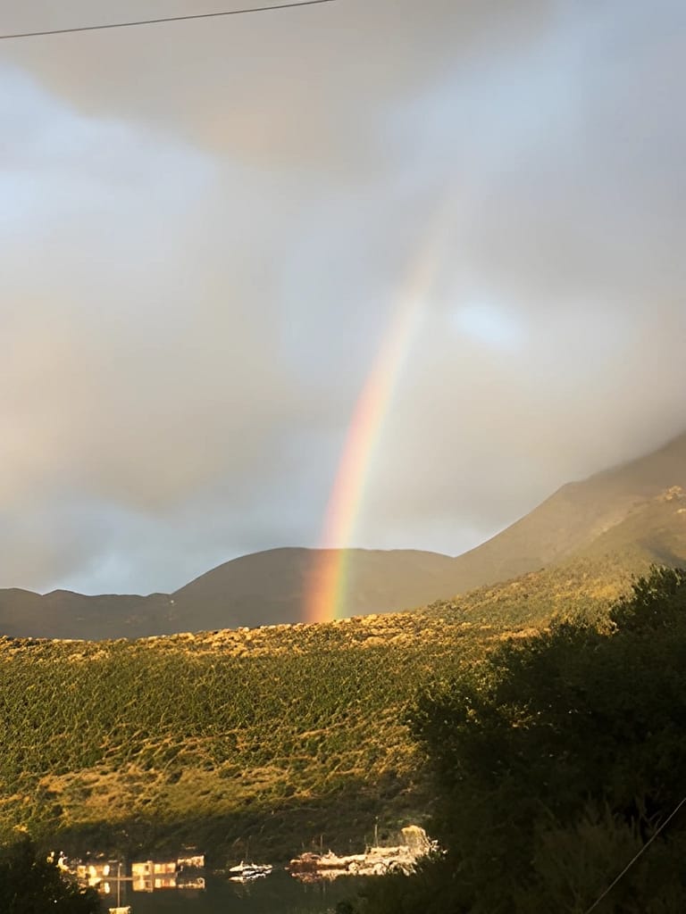 Vista serena delle isole del Principe, con la baia che riflette i colori di una mattinata nuvolosa rasserenata da un bel arcobaleno