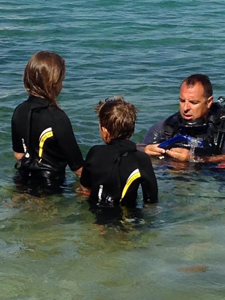 Christos, il fondatore del Lefkas Diving Center, durante una lezione con due bambini, trasmettendo loro le basi delle immersioni subacquee in un ambiente sicuro e accogliente.