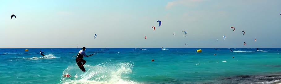 Kiters che praticano il kitesurf nelle acque di Agios Ioannis, in piena attività sotto il sole estivo.