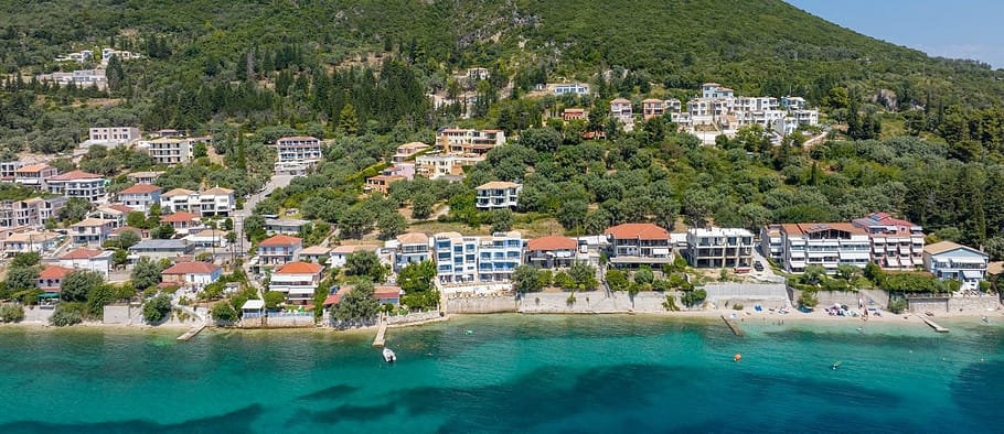 Vista della costa di Perigiali dal mare con il Greek Beach House al centro, immerso tra acque dai colori smeraldini e sfumature turchesi.